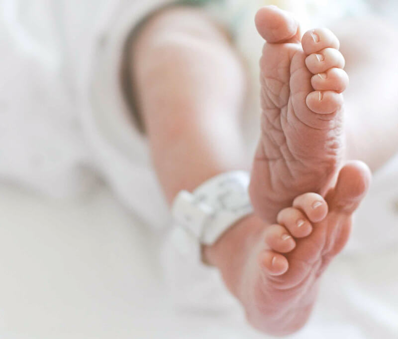 An infant's feet , seen in a GE Panda Warmer.